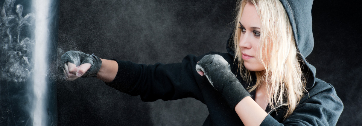 Blond boxing woman in black punching bag